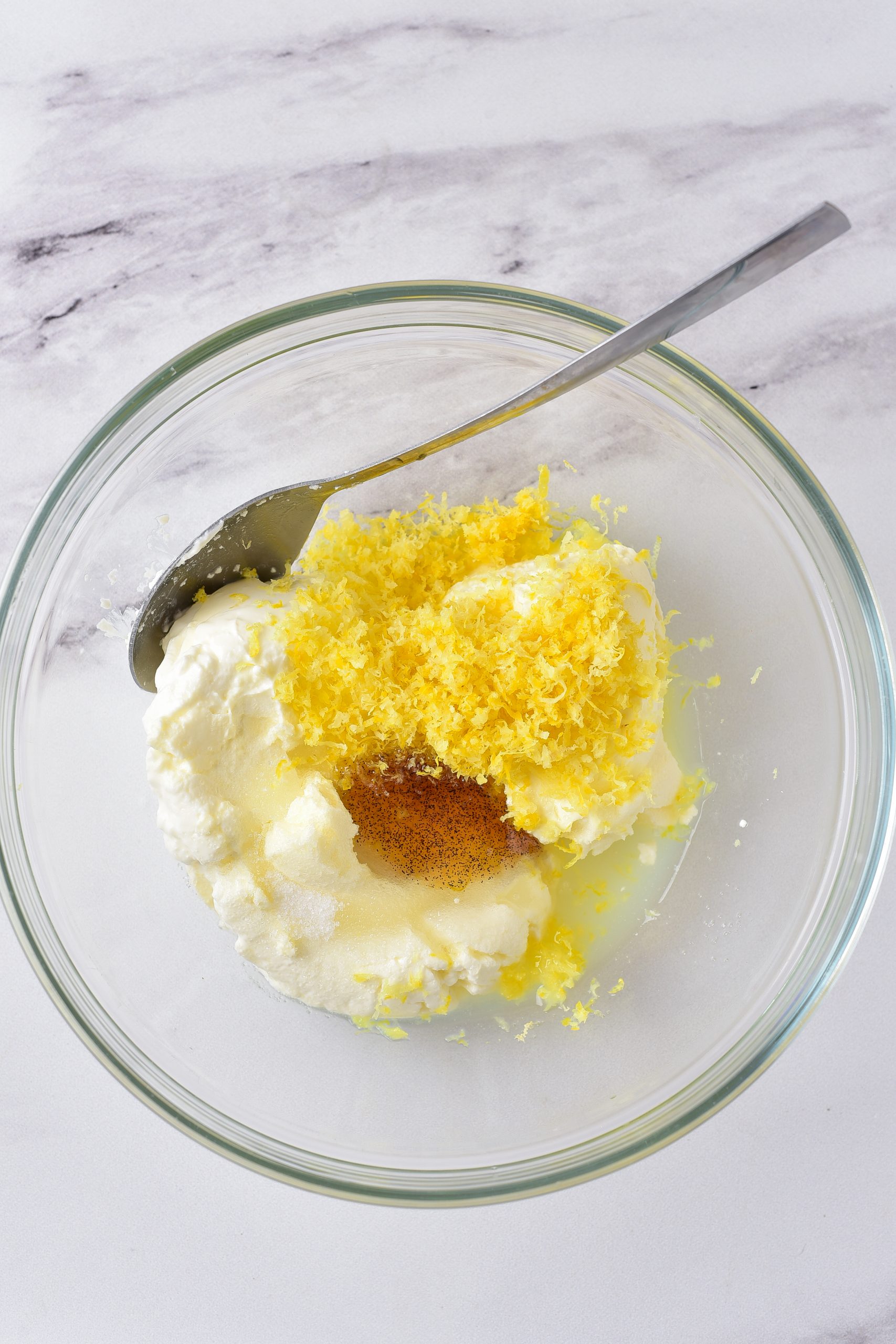 add the cream cheese, vanilla, lemon juice, lemon zest, and ½ cup of sugar to a mixing bowl