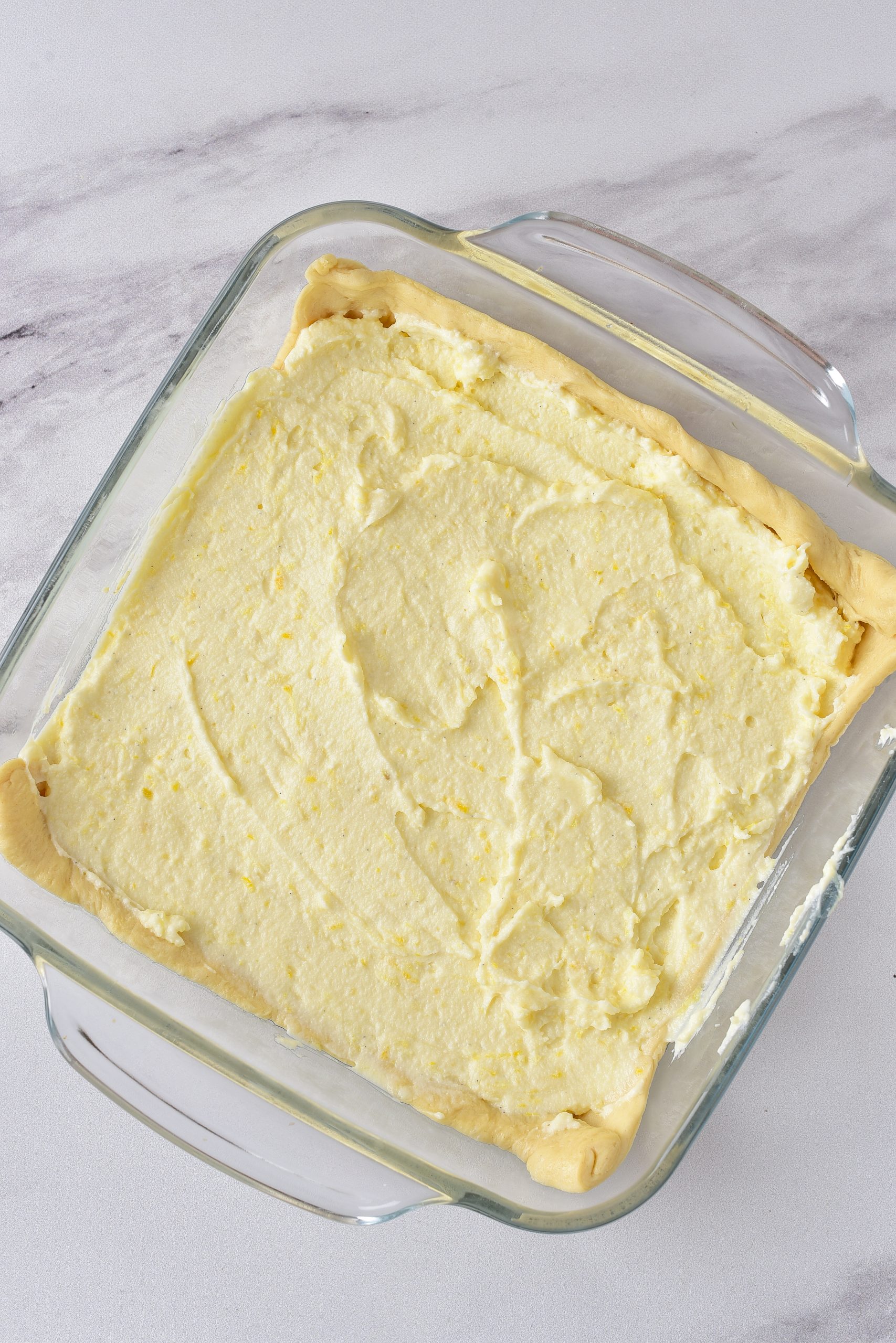 Spread the cream cheese mixture over the layer of dough in the baking dish