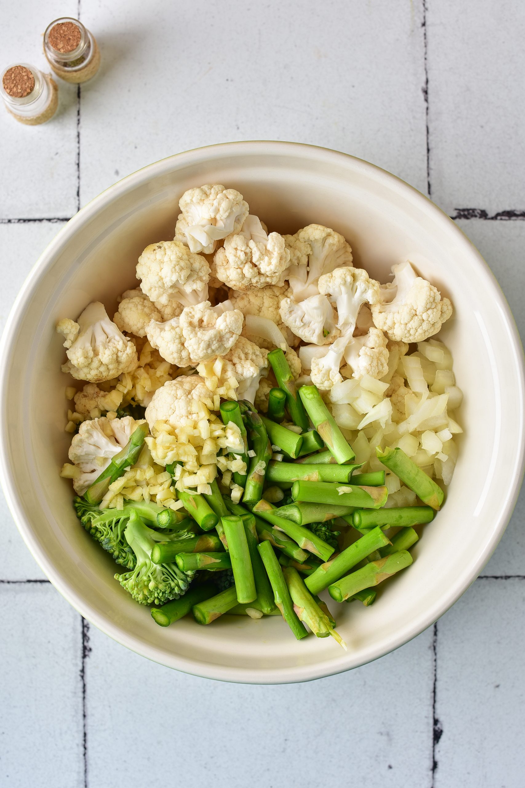 In a bowl, combine the asparagus, cauliflower, broccoli, and onion. 