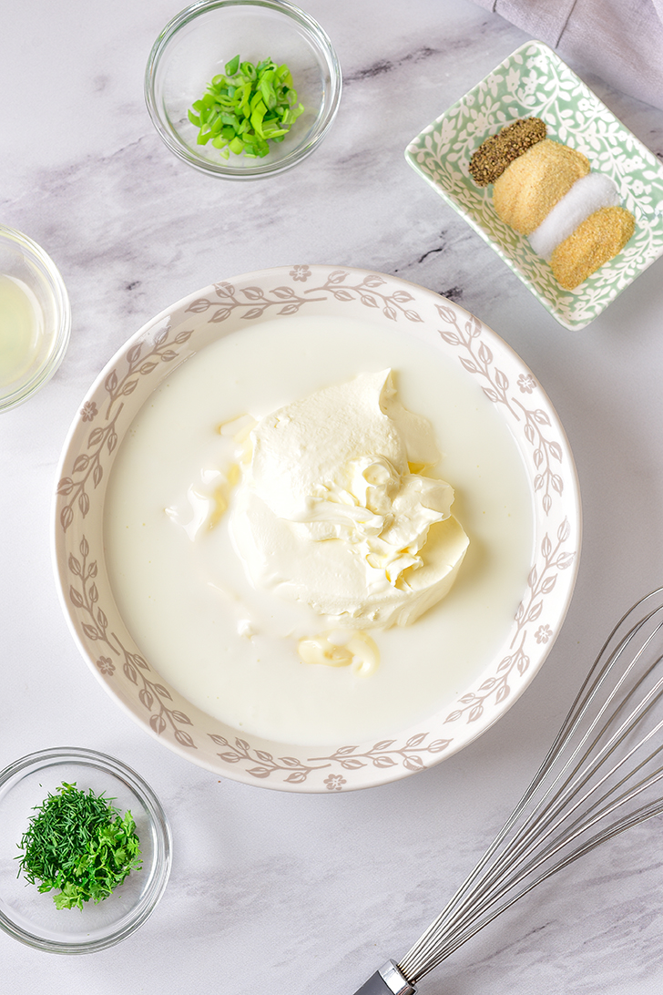 Whisk together the buttermilk, mayonnaise, and sour cream in a mixing bowl.