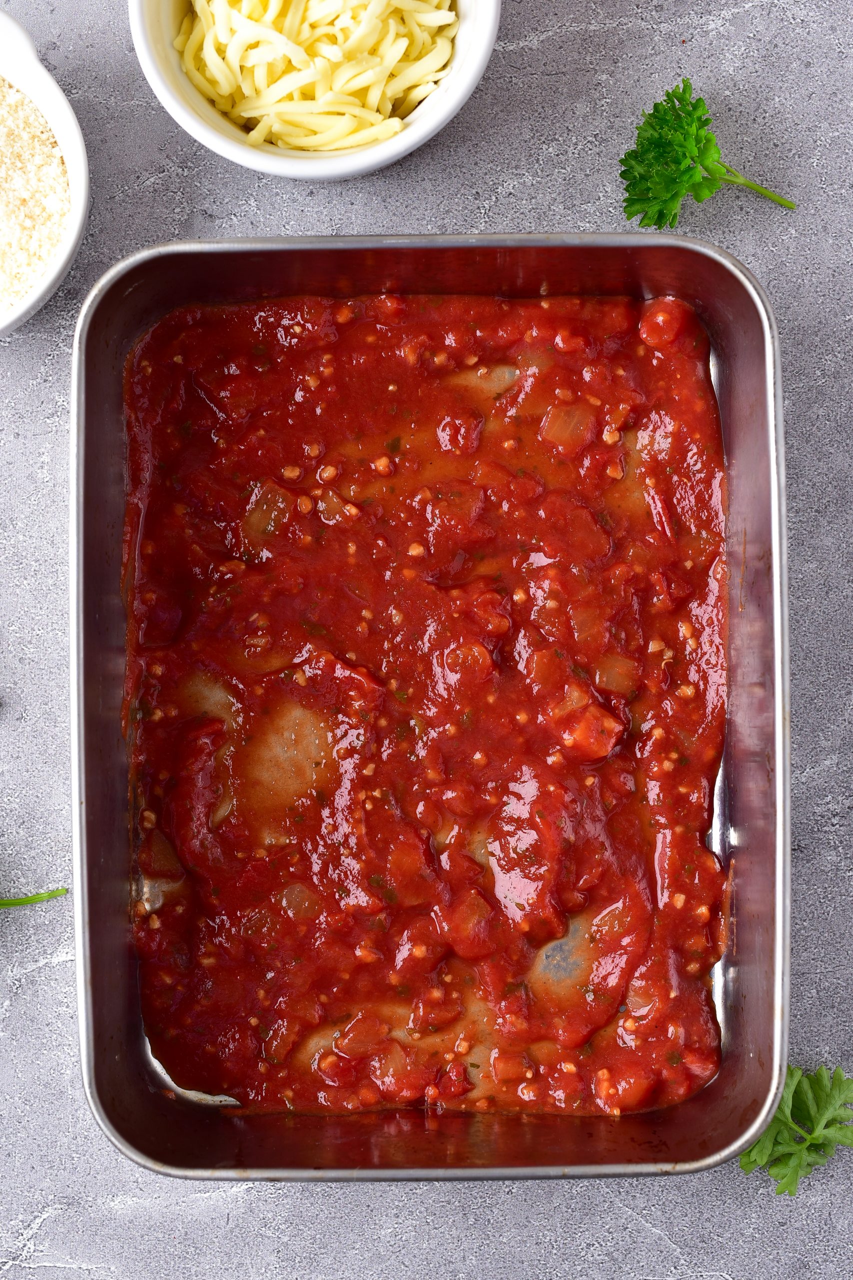 Spread half a jar of sauce into the bottom of the baking sheet. 