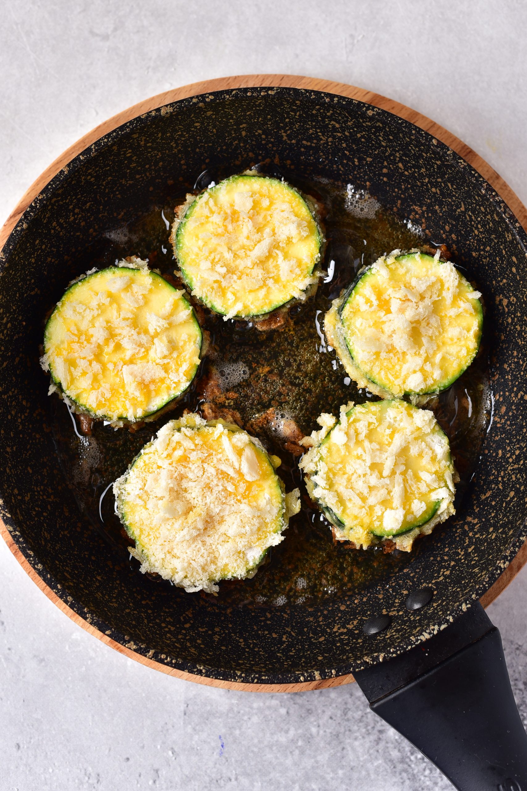 Fry the zucchini slices in the heated oil for 4-5 minutes until golden brown on both sides.