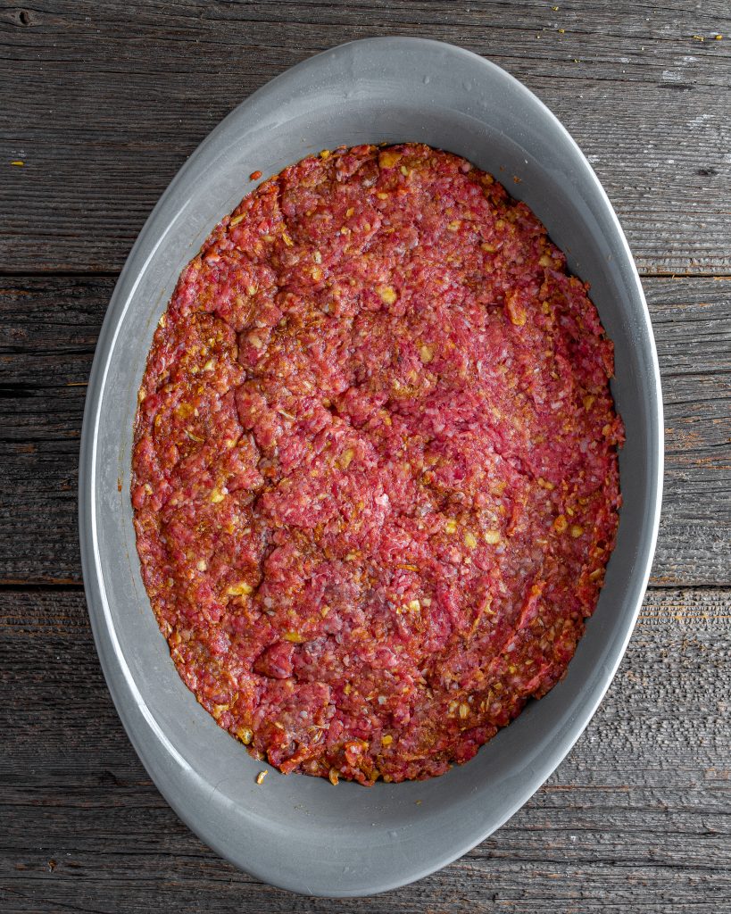 Press the meat mixture into an even layer in the bottom of the baking dish. 