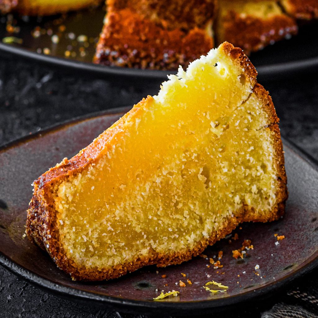 A golden-brown Lemon Cream Cheese Pound Cake topped with a thick white glaze.